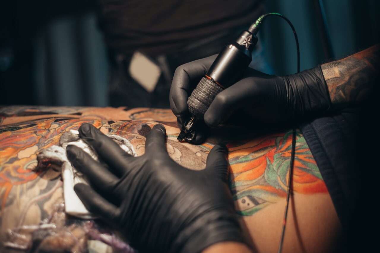 Hands,Of,A,Tattoo,Artist,Wearing,Black,Gloves,And,Holding