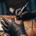 Hands,Of,A,Tattoo,Artist,Wearing,Black,Gloves,And,Holding